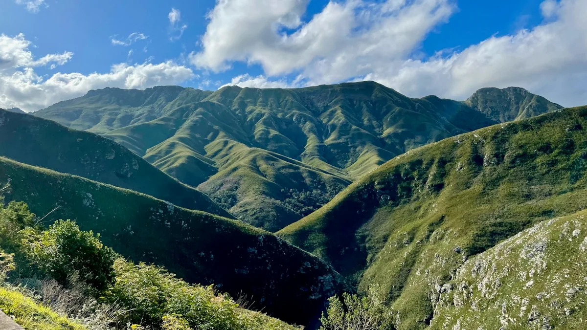 A green mountain valley beneath a clouded blue sky